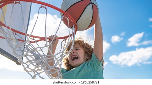 Close Up Image Of Kid Basketball Player Making Slam Dunk During Basketball Game In Floodlight Basketball Court. The Child Player Is Wearing Sport Clothes.