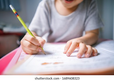 Close Up Image Of Little Kid Hands Holding Pencil Writing  And Doing Home Work On Class Book