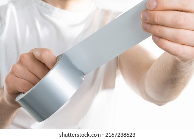 Close up image of man holding adhesive duct tape white background. male hands trying to fix something.