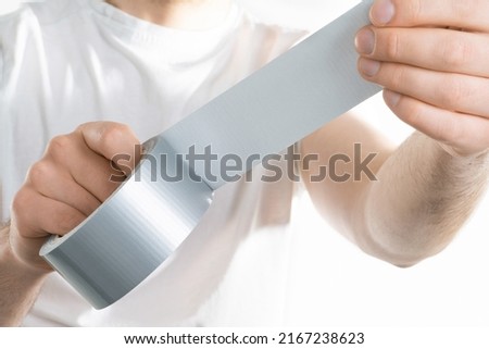 Close up image of man holding adhesive duct tape white background. male hands trying to fix something.