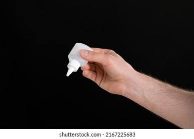 A Close Up Image Of Man's Hand Holding A Bottle Of Glue Isolated On Black Background