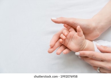 Close up image of a mother`s mom hand holding her little small toddler`s infant newborn tiny hand on white background. Childcare, motherhood concept. - Shutterstock ID 1992076958
