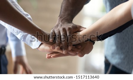 Close up image multiracial people standing in circle, joining hands in middle, showing support, demonstrating mixed race team unity. Group of diverse people involved in team building activity.