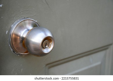 A Close Up Image Of An Old And Dirty Metal Door Knob On A Greyish-green Painted Door.