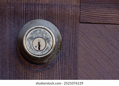 A close up image of an old and grungy security door lock on a wooden door.  - Powered by Shutterstock