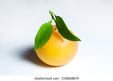 Close Up Image Of One Juicy Organic Whole Grapefruit With Green Leaves & Visible Zest Texture, Isolated White Background, Copy Space. Macro Shot Of Single Bright Citrus Fruit. Top View, Flat Lay.