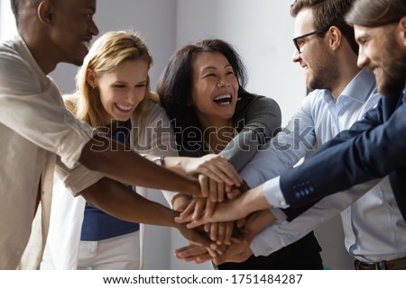 Close up image overjoyed 5 multi ethnic business people stack touch arms palms together celebrating promotion reward, succeed common aim. Give high five symbol of unity, team building activity concept