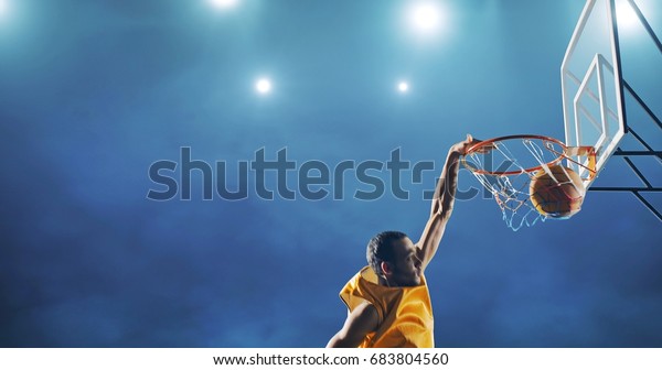 Close up image of\
professional basketball player making slam dunk during basketball\
game in floodlight basketball court. The player is wearing\
unbranded sport clothes.