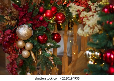 Close up image railing of wooden staircase decorated Christmas with multicilired glass balls, garland, mistletoe and spruce branches. Home Christmas and New Year decor.
