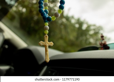 Close up image of Rosary beads hanging Inside a Car