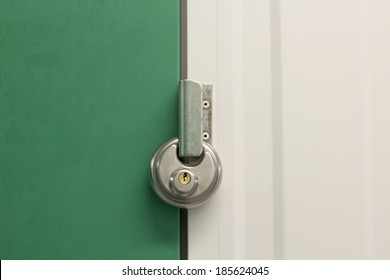 Close Up Image Of A Round Heavy Duty Pad Lock On A Self Storage Unit With A Green Door