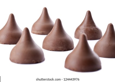 Close up image of scattered chocolate kisses against white background