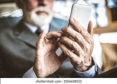 Close Up Image Of Senior Businessman Using Mobile Phone.  Focus On Hand. 