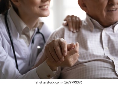 Close up image smiling friendly positive nurse in white coat stethoscope on neck hold hand hugs of old man patient. Social worker, eldercare, geriatric medicine, medical insurance, health care concept - Shutterstock ID 1679793376