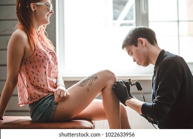 Close Up Image Of The Tattoo Male Artist Makes A Tattoo On A Female Leg.