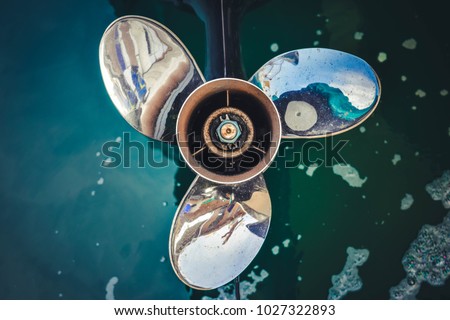 Close up image of  Three bladed stainless steel Boat Engine propeller in the water background.