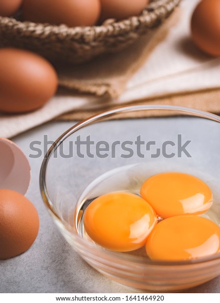Close up image of three eggs yolk in clear bowl\
are one of the food ingredients on the restaurant table in the\
kitchen to prepare for cooking. Organic chicken eggs food\
ingredients concept