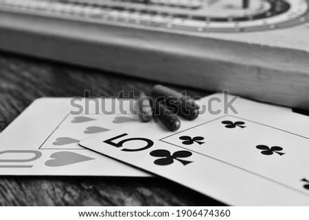 A close up image of two playing cards with cribbage pegs and cribbage board. 