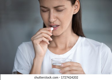 Close Up Image Of Unhealthy 35s Female Closed Eyes Suffers From Migraine Or Hangover Holds Glass Of Water Takes Painkiller Pill For Throbbing Headache Reducing, Medical Abortion Hard Decision Concept