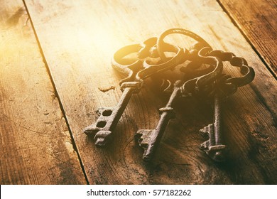 close up image of vintage skeleton keys over wooden table and bright light as revelation concept - Shutterstock ID 577182262
