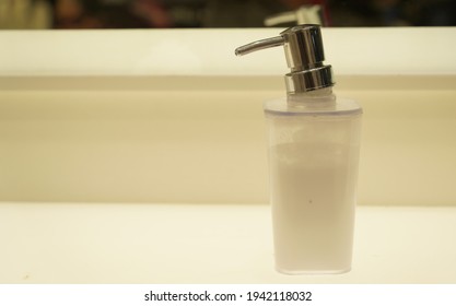 Close Up Image Of A White Glass Soap Dispenser Squeezer With Steel Head 