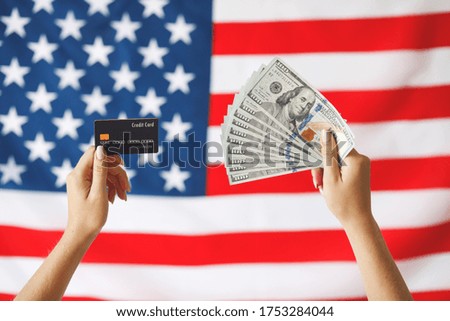 Close up image of woman hands with american dollars and  and credit card. Girl holding money on American flag background. 