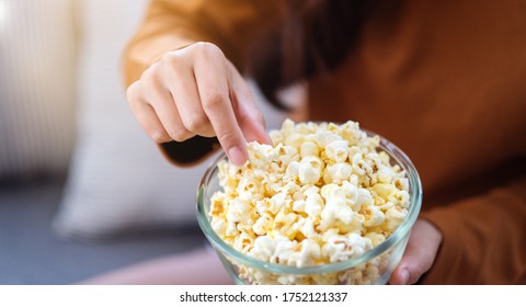 Close Up Image Of A Woman Holding And Picking Pop Corn From A Bowl To Eat While Sitting On Sofa At Home