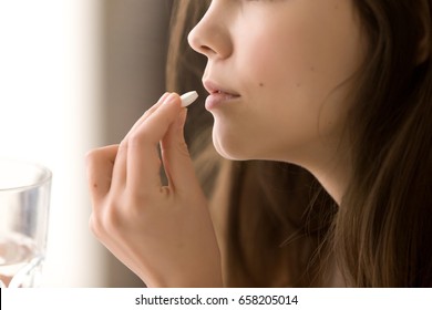 Close Up Image Of Woman Putting White Round Pill In Mouth. Sick Female Taking Medicines, Antidepressant, Painkiller Or Antibiotic. Young Lady Drinking Contraceptives. Pharmacy And Healthcare Concept