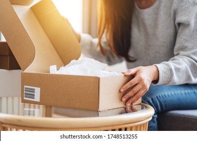 Close up image of a woman receiving and opening a postal parcel box at home for delivery and online shopping concept