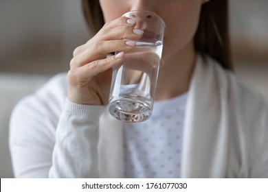 Close up image woman sit indoors holds glass of still or mineral water drinking clean aqua reducing thirst. Healthy lifestyle life habits, enough quantity every day for beauty skin health care concept - Shutterstock ID 1761077030
