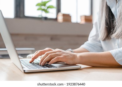 Close up image of woman`s hands typing on laptop at the desk