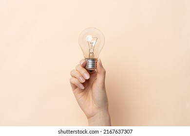 A close up image of wonas hand with light bulb isolated on beige background