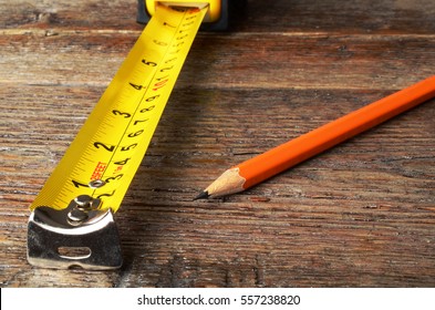 A close up image of a yellow carpenters tape measure and one wooden pencil.