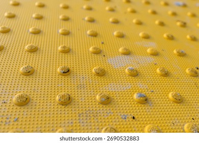 Close up image of a yellow detectable warning surface, tactile plate at a ADA crosswalk.	