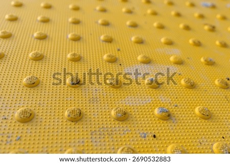 Close up image of a yellow detectable warning surface, tactile plate at a ADA crosswalk.	