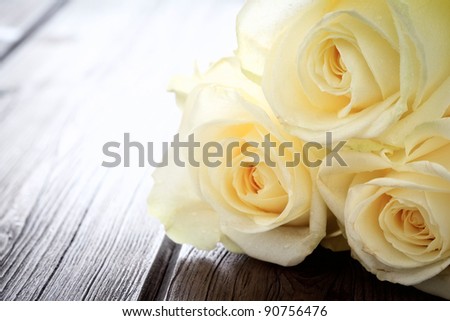 Close up image of yellow roses petals on a wooden background with copy space.