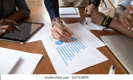 Close up image young businessman holding pen, editing paper documents with printed documents, explaining marketing strategy or planning company economic growth at brainstorming meeting at office.