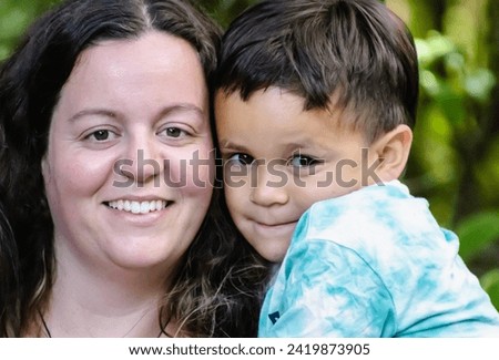 a close up image of a young Maori boy posing for a photograph with his white mother.