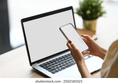 Close up image of young woman using smartphone in front of her laptop. - Powered by Shutterstock