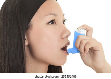 A Close up image of a young woman using inhaler.