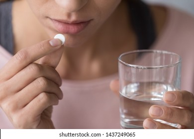 Close Up Of Indecisive Young Woman Hold Pill And Glass Of Water Doubt About Emergency Medication, Hesitant Sick Female Suffering From Depression Consider Taking Antidepressant. Health Problem Concept