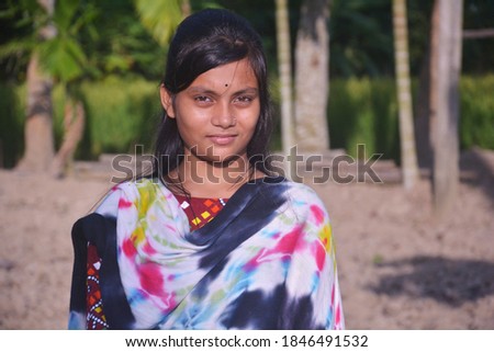 Close up of an Indian Bengali teenage girl with long dark hairs wearing traditional dress salwar kameez in agricultural field, selective focusing