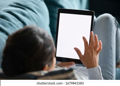 Close Up Indian Female Typing On Computer Tablet Screen Blank White Mockup, Relaxing On Cozy Sofa At Home, Young Female Holding Electronic Device, Surfing Internet, Reading Book, Chatting Online