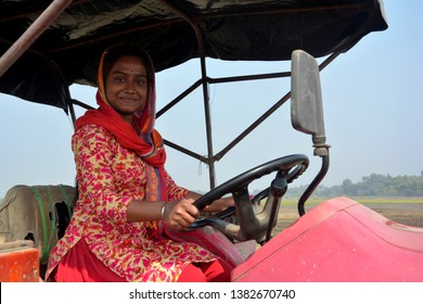 Close up of  an Indian girl sitting on a tractor in the field with sky in the background, selective focusing.