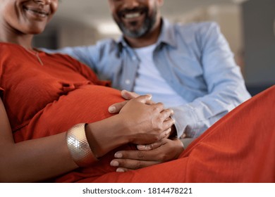 Close up of indian man feeling pregnant woman stomach. Mid adult couple expecting child while father touching baby bump. Close up hands of happy expectant mixed race couple feeling baby movement.