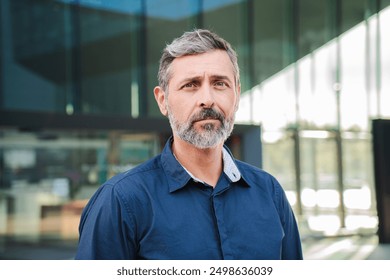 Close up individual portrait of a mature and formal business man with a reliable and confident attitude, looking seriously at the camera. A middle-aged male wearing a shirt staring front thoughtfully - Powered by Shutterstock