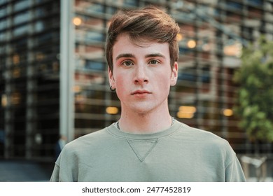 Close up individual portrait of one young male standig outside and looking at camera with serious expression. Teenage student staring front with pensive attitude. Headshot of a isolated real guy. High - Powered by Shutterstock