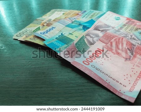 Close up of Indonesian rupiah banknotes in one hundred, fifty, ten, five and two thousand denomination isolated on wooden background. Cash management concept.