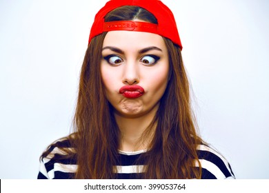 Close Up Indoor Fashion Lifestyle Portrait Of Cool Pretty Young Brunette Girl, Amazing Long Hairs, Bright Makeup, Red Hat And Stripy T Shirt, Cute Face, Image With Flash. Making Crazy Funny Grimace.