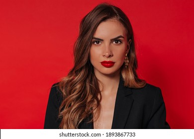 Close up indoor portrait of spectacular stylish woman with evening make up posing over red background and celebrating Valentine's day 